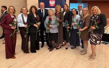 Wyr&oacute;żnione osoby pozują z medalami i kwiatami