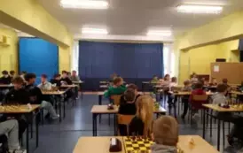 Uczniowie siedzą przy stolikach szachowych